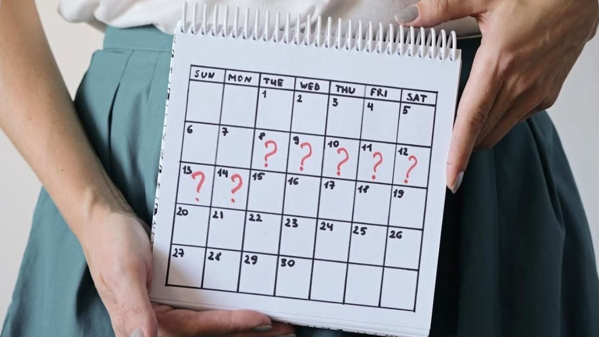 Calendário com datas marcadas com pontos de interrogação, representando a irregularidade do ciclo menstrual